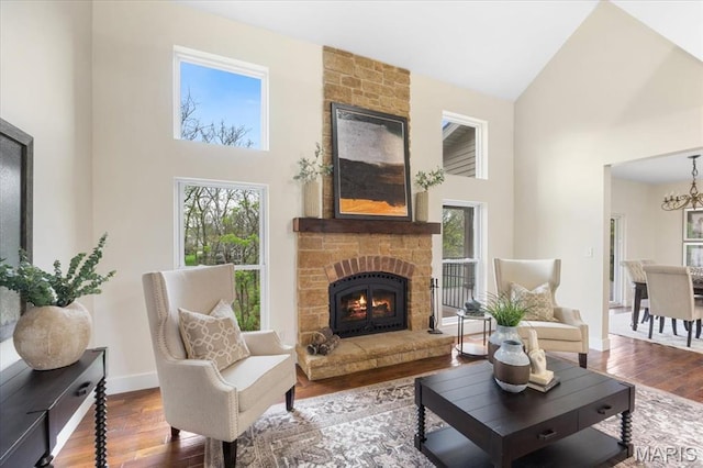 115 Place De Yeager, Lake St Louis, MO 63367 - living room featuring high vaulted ceiling, a stone fireplace, wood finished floors, a chandelier, and baseboards
