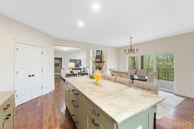 115 Place De Yeager, Lake St Louis, MO 63367 - kitchen featuring dark wood-style flooring, a chandelier, open floor plan, a center island, and baseboards