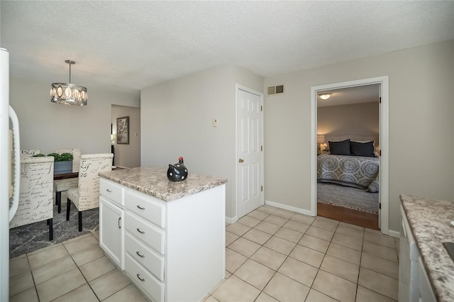 133 Lithia Ave, Saint Louis, MO 63119 - kitchen with white cabinets, light tile patterned floors, a center island, a chandelier, and a textured ceiling