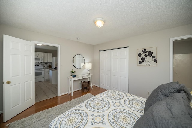 133 Lithia Ave, Saint Louis, MO 63119 - bedroom with wood finished floors, a closet, a textured ceiling, ensuite bath, and freestanding refrigerator