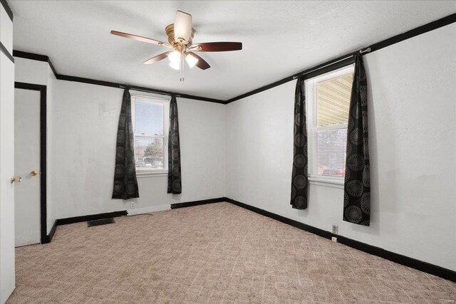 carpeted spare room with ceiling fan, crown molding, and baseboards