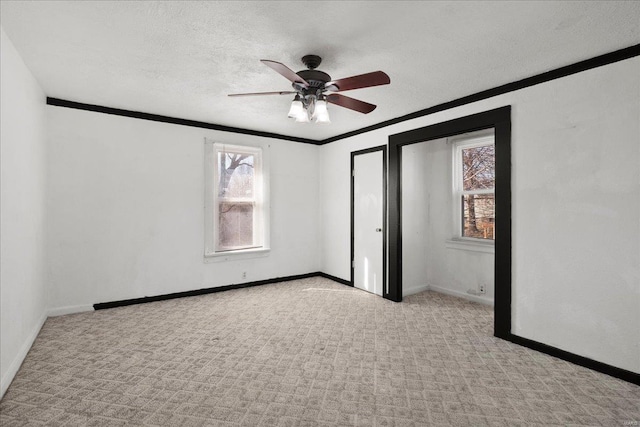 unfurnished bedroom featuring ornamental molding, carpet flooring, a textured ceiling, baseboards, and a ceiling fan