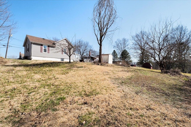 view of green lawn featuring a storage shed and an outdoor structure