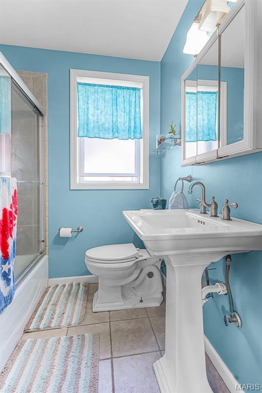 5800 Marquette Ave, Saint Louis, MO 63139 - full bathroom with toilet, tile patterned flooring, combined bath / shower with glass door, and baseboards