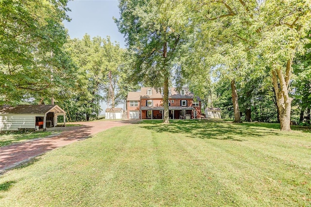 view of green lawn with stairs, driveway, and an outdoor structure