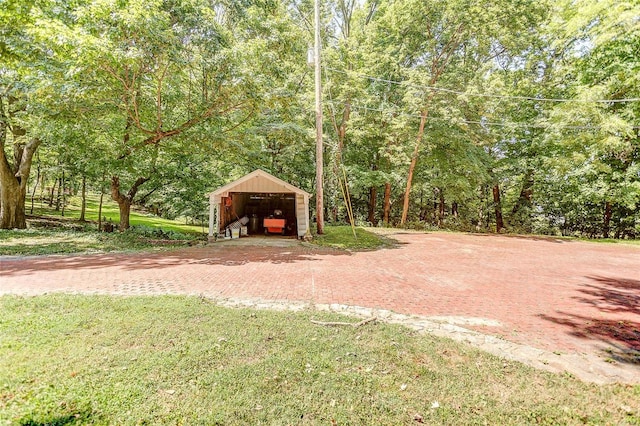 view of grassy yard with a detached garage, an outdoor structure, and an outbuilding