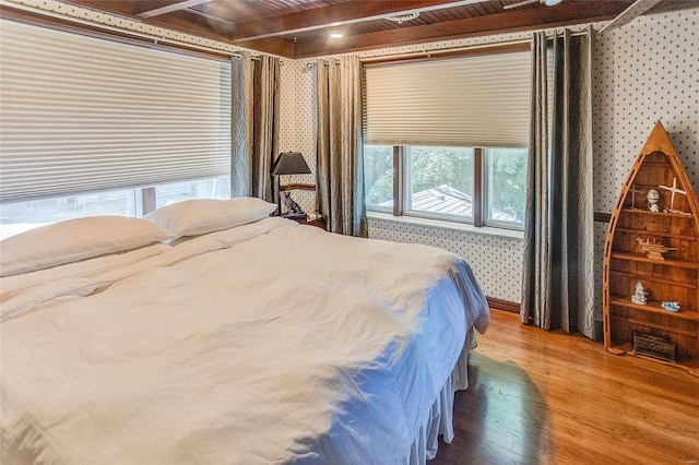 bedroom with wood finished floors and beam ceiling