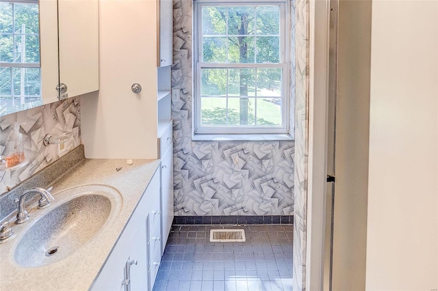 bathroom with healthy amount of natural light, vanity, and tile patterned flooring