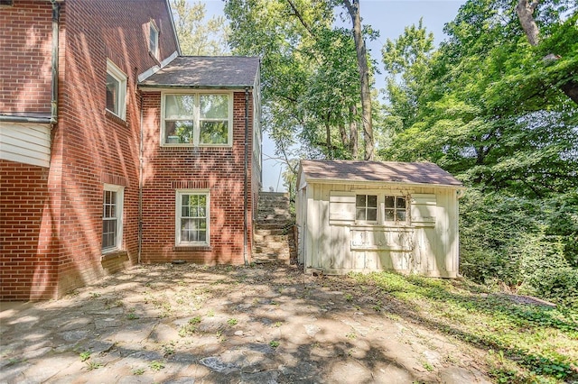 view of property exterior featuring a storage shed, an outbuilding, and brick siding