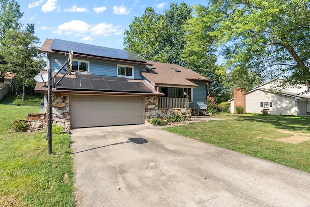 split level home featuring stone siding, roof mounted solar panels, a front lawn, driveway, and roof with shingles