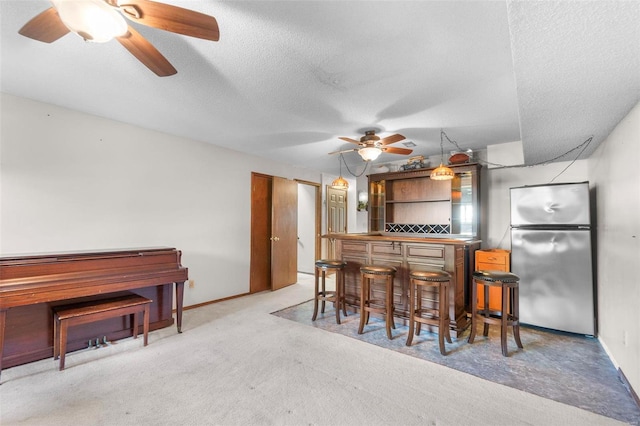kitchen featuring freestanding refrigerator, a ceiling fan, carpet, a textured ceiling, and baseboards