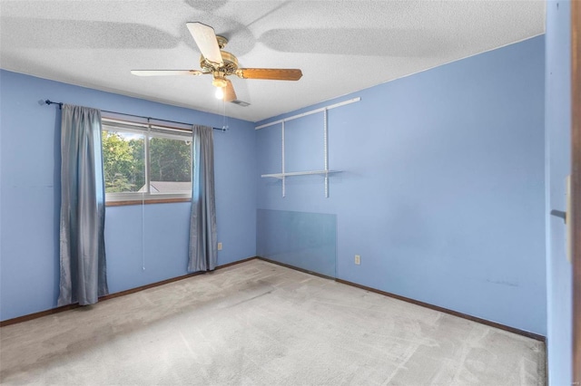 carpeted spare room with ceiling fan, a textured ceiling, and baseboards