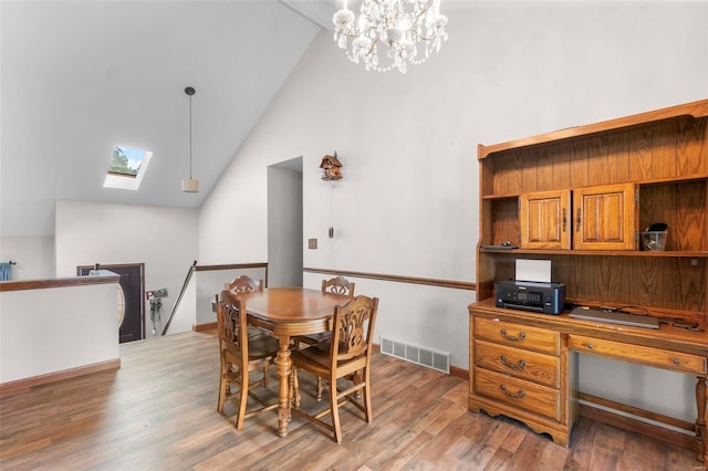 dining room featuring a skylight, light wood-style floors, a chandelier, an office area, and high vaulted ceiling