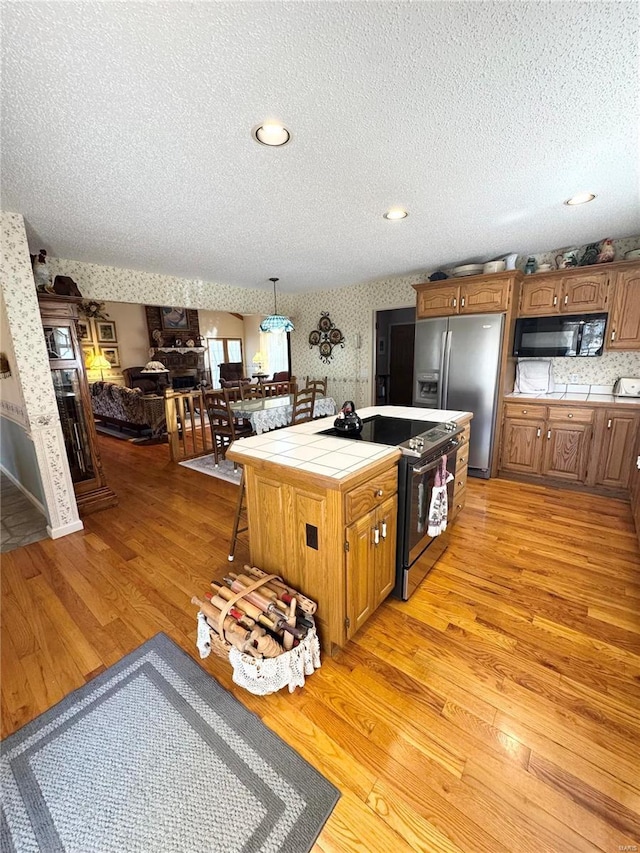 4 N Missouri Ave, Salem, MO 65560 - kitchen with appliances with stainless steel finishes, tile countertops, light wood-type flooring, a textured ceiling, and brown cabinets
