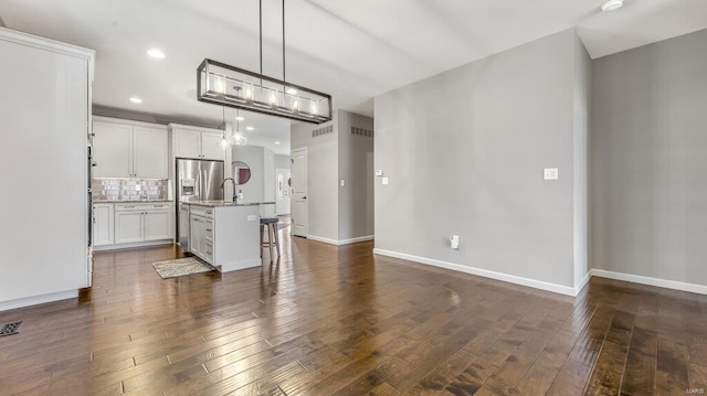 unfurnished living room with dark wood-style floors, baseboards, recessed lighting, and a sink