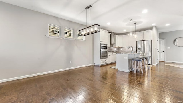kitchen with stainless steel appliances, recessed lighting, backsplash, an island with sink, and baseboards