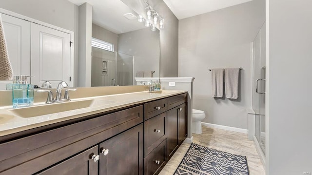 bathroom featuring a shower stall, double vanity, baseboards, and toilet