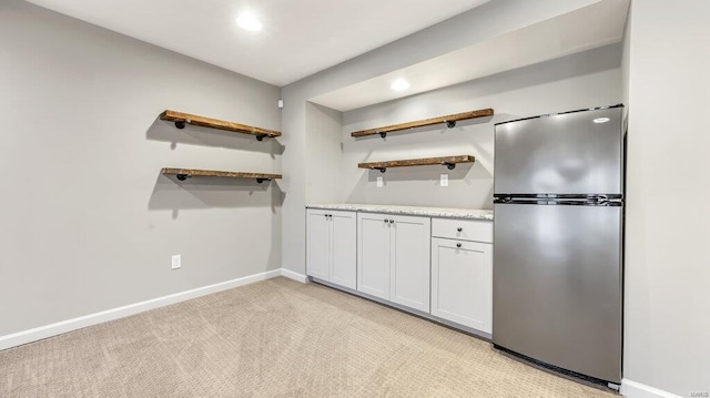 kitchen with freestanding refrigerator, open shelves, baseboards, light countertops, and light colored carpet