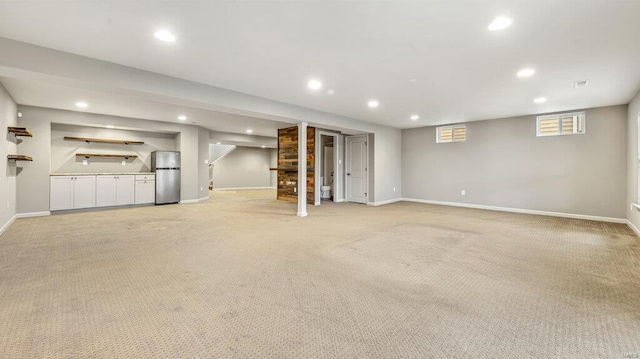 basement with freestanding refrigerator, recessed lighting, light colored carpet, baseboards, and stairway
