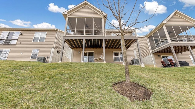 rear view of property featuring a sunroom, central air condition unit, and a lawn