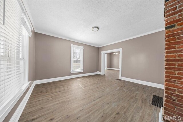 307 S State Highway 47, Warrenton, MO 63383 - unfurnished living room with a textured ceiling, a chandelier, wood finished floors, baseboards, and crown molding