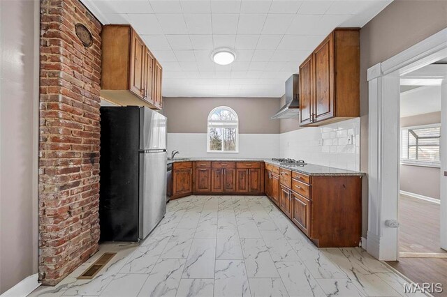 307 S State Highway 47, Warrenton, MO 63383 - kitchen featuring appliances with stainless steel finishes, wall chimney range hood, brown cabinets, and light marble finish flooring