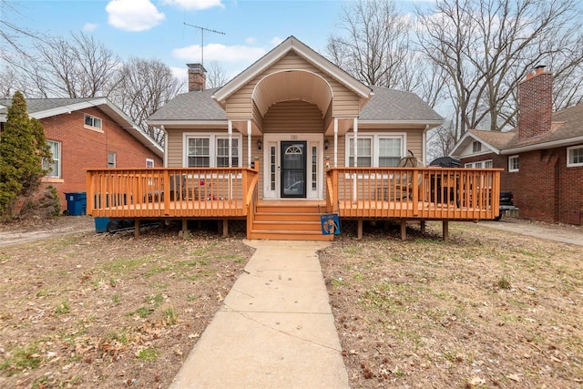 bungalow featuring a wooden deck, a chimney, and a shingled roof