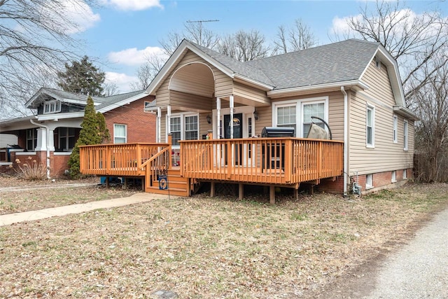 view of front facade with a wooden deck and roof with shingles
