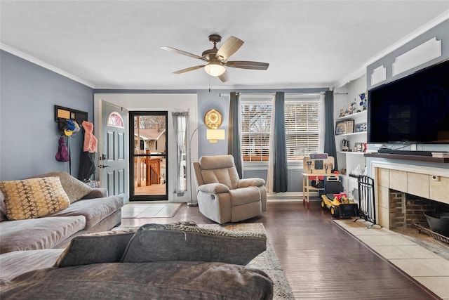 living area with ornamental molding, ceiling fan, a fireplace, and wood finished floors