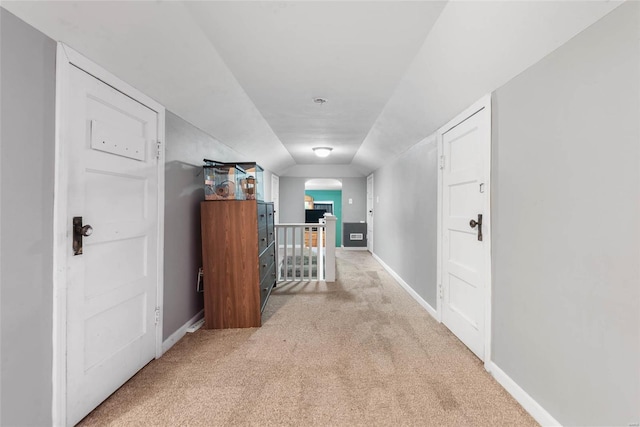 corridor with light carpet, arched walkways, baseboards, and an upstairs landing