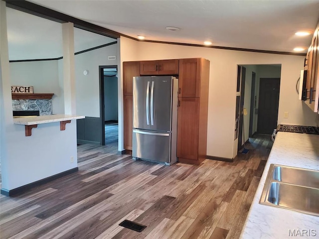 19983 Oak Dr, Carlyle, IL 62231 - kitchen with freestanding refrigerator, dark wood finished floors, light countertops, brown cabinetry, and a kitchen breakfast bar