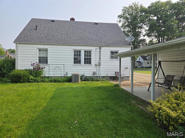 1450 Mulliken St, Carlyle, IL 62231 - back of house with central AC unit, a yard, a patio, roof with shingles, and a chimney