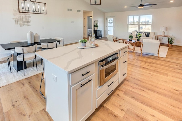 kitchen with light wood-type flooring, white cabinets, a kitchen island, recessed lighting, and lofted ceiling