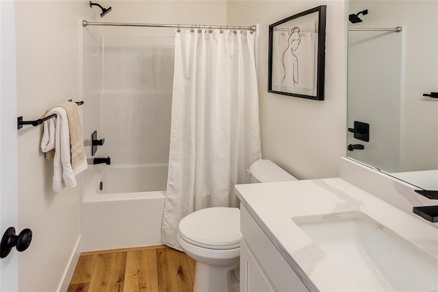 bathroom featuring toilet, wood finished floors, vanity, and shower / tub combo