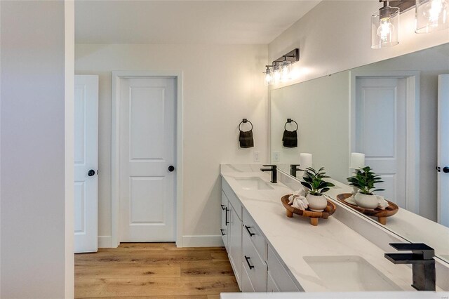 full bath with wood finished floors, double vanity, and baseboards