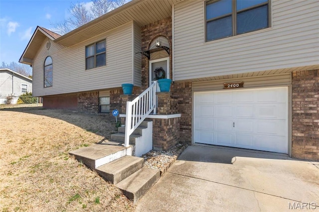 bi-level home with an attached garage, brick siding, and driveway