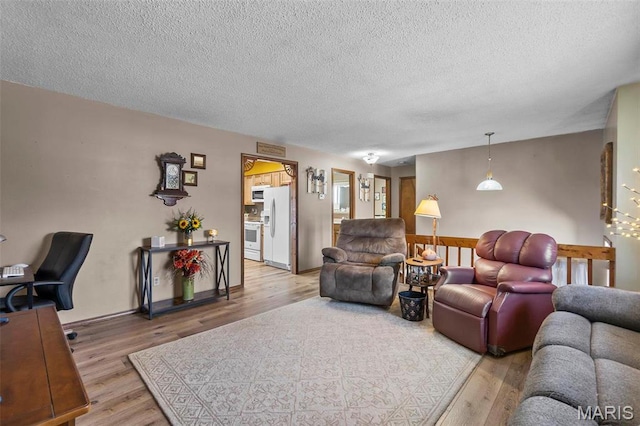 living area with light wood-type flooring and a textured ceiling