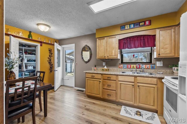 kitchen with white electric stove, a sink, light countertops, a textured ceiling, and light wood-style flooring