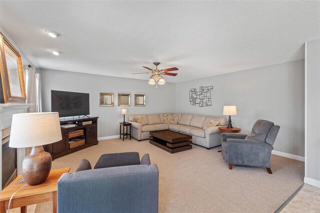 living room with carpet floors, baseboards, ceiling fan, and a fireplace