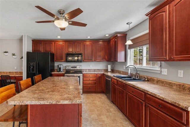 kitchen with black appliances, a sink, a breakfast bar, a ceiling fan, and pendant lighting