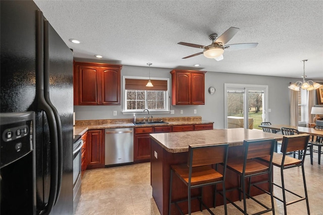 kitchen featuring stainless steel appliances, a sink, a ceiling fan, pendant lighting, and a textured ceiling