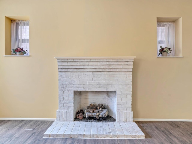 detailed view of wood finished floors, a fireplace, and baseboards