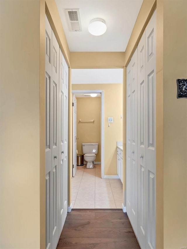 hall featuring light wood-style flooring and baseboards