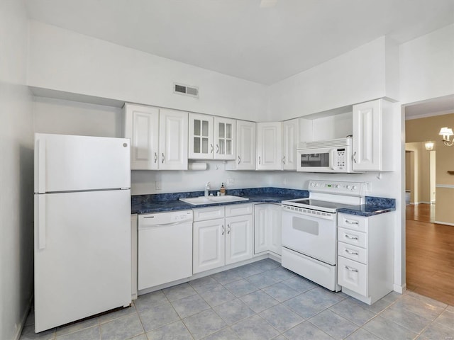 kitchen featuring white appliances, a sink, dark countertops, white cabinetry, and a chandelier