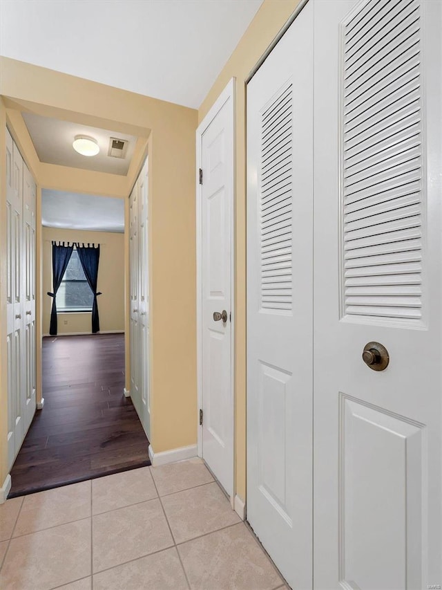 corridor with light tile patterned floors and baseboards