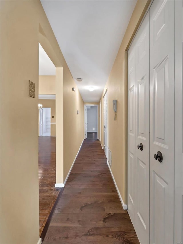 hallway with dark wood-style flooring and baseboards
