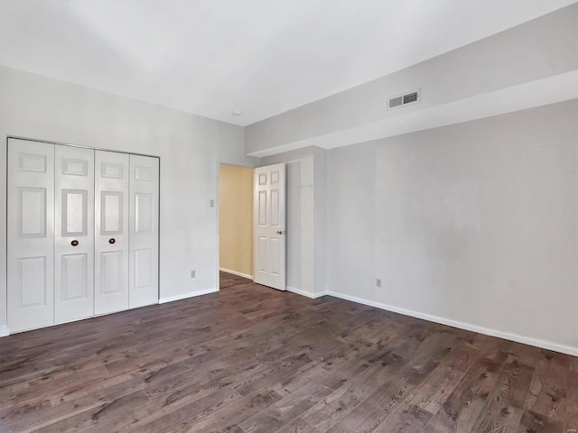 unfurnished bedroom featuring dark wood-style floors, baseboards, and a closet