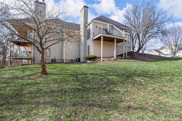 rear view of property with a chimney, a balcony, a yard, and cooling unit