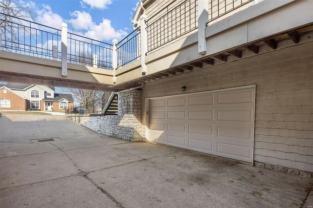 view of side of property with a garage, driveway, a balcony, and stone siding