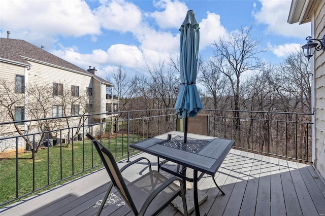 wooden terrace featuring outdoor dining space and a lawn